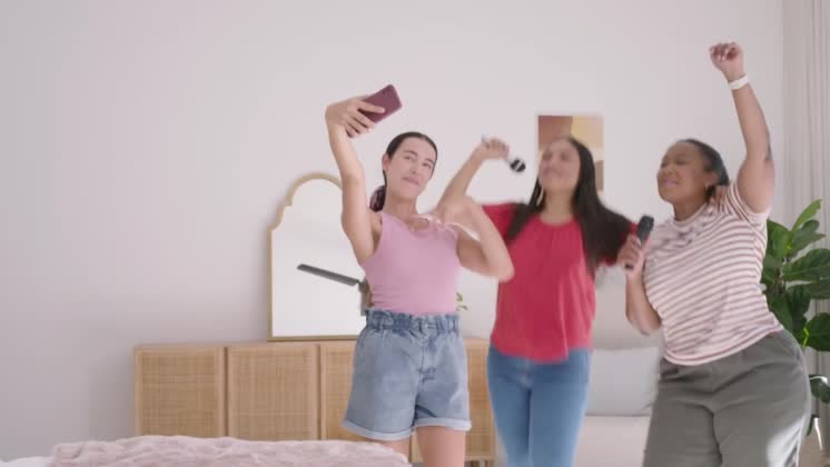 VIDEO: Diverse female friends posing for selfie, holding phone and checking screen, singing with mic props Diverse female friends posing for selfie, holding phone and checking screen, singing with mic props. Candid, trio, karaoke, dance, friendship, interior, bright, shootlocation: Cape Town, South Africa, shootdate: 2026-03-31, model released, property released Ref:14388641