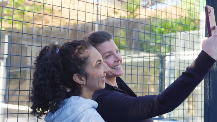 VIDEO: Diverse female friends posing for selfie, right friend holding pink smartphone and smiling at court Diverse female friends posing for selfie, right friend holding pink smartphone and smiling at court. Outdoor, sunny, friendship, togetherness, candid, casual, fence, shootlocation: Cape Town, South Africa, shootdate: 2026-06-09, model released, property released Ref:15884422